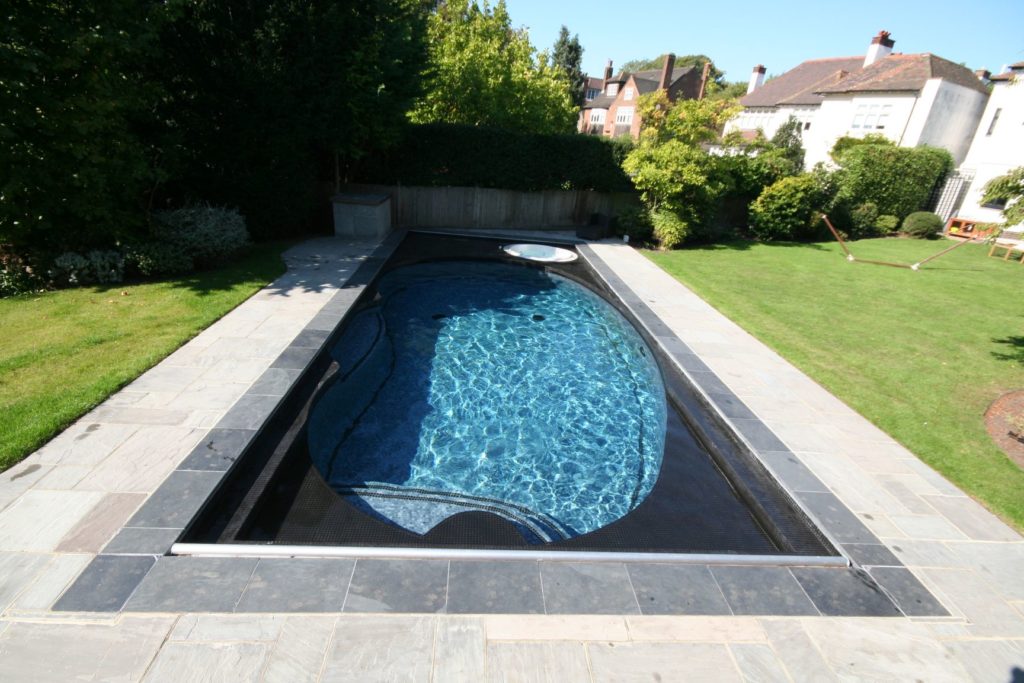 Major rebuild of an outdated 70's kidney shaped pool by lowering the sides and "sinking the original pool" to retile and add safety cover, ledges and spa.
