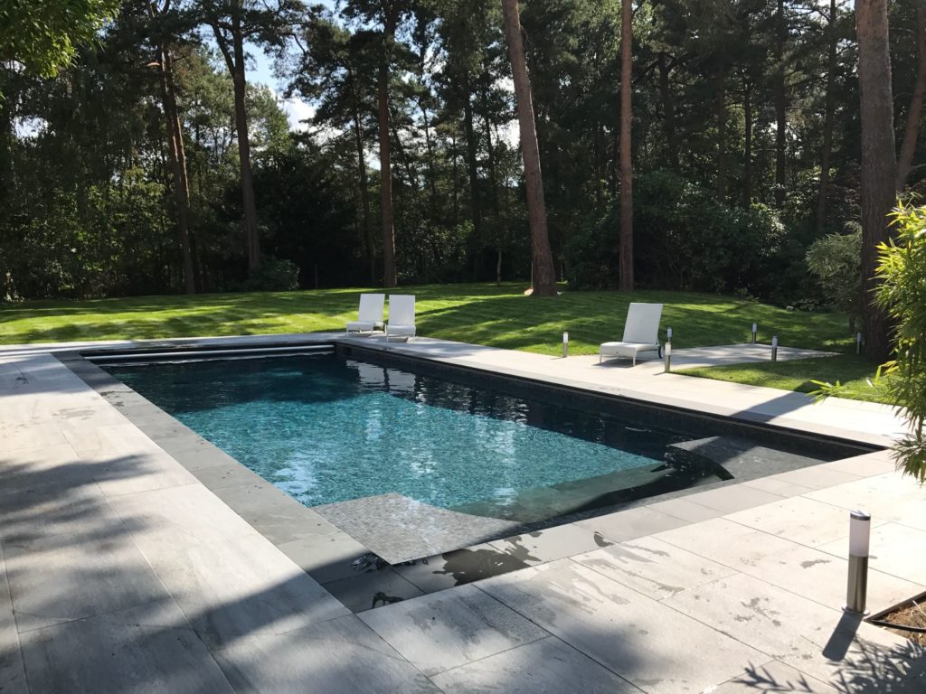 Originally a classical Roman ended pool in dated 70's tiles, we have "sunk" the end to enable the fitting of an automatic safety cover, re-tiled in contemporary charcoal mosaics and slate steps and coping stones.