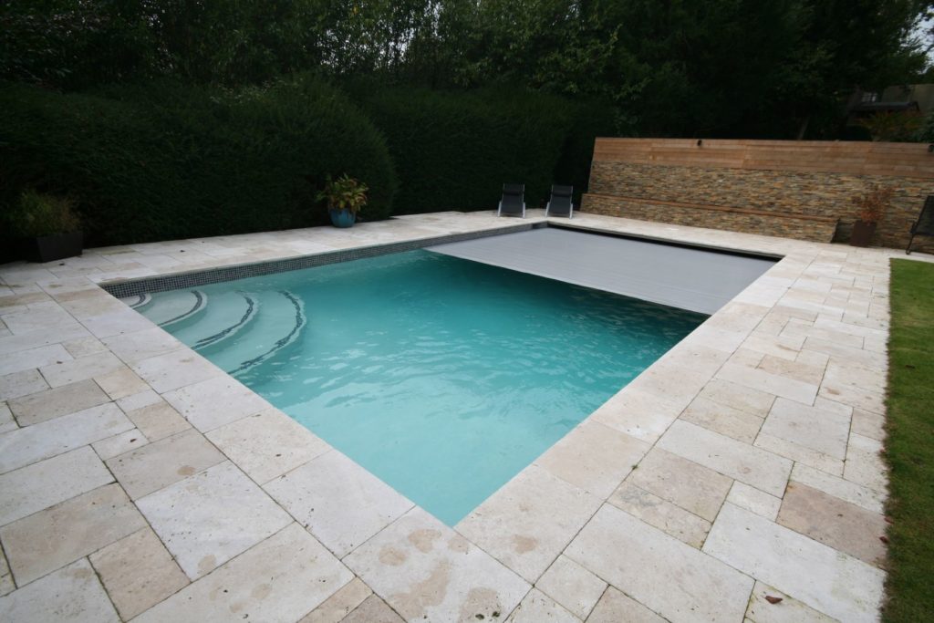 Muted tones of ivory tiles with contrasting tileband and marker lines and natural coloured paving and automatic slatted cover