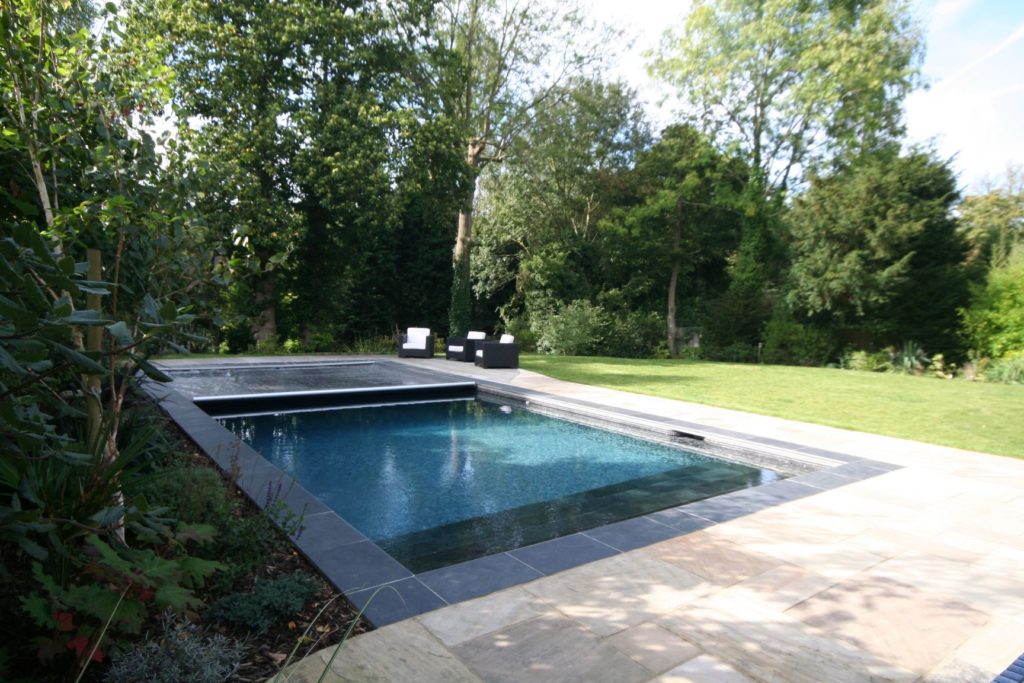 Contemporary charcoal mosaic tiles and slate steps and coping stones with dark grey automatic safety cover gives this pool a stylish edge