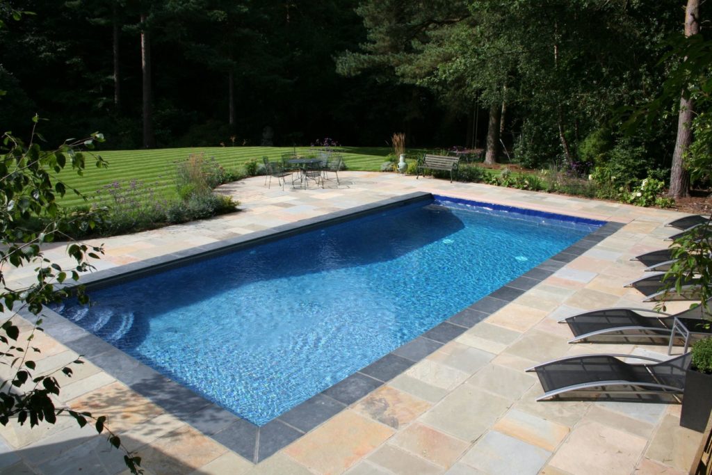 Simplicity of styling with a blue automatic safety cover and sanstone paving and quadrant steps