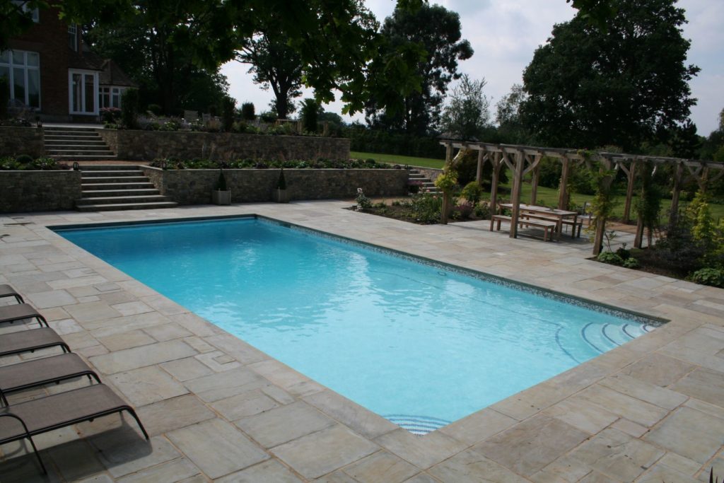 Muted tones in this outdoor pool with automatic safety cover and tile band reflecting the garden walling